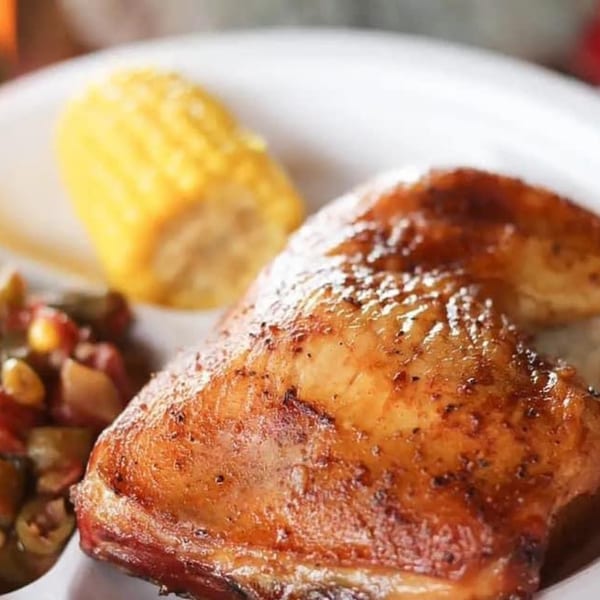 Hank's Catfish & BBQ's grilled chicken leg quarter, corn on the cob, and side dish.