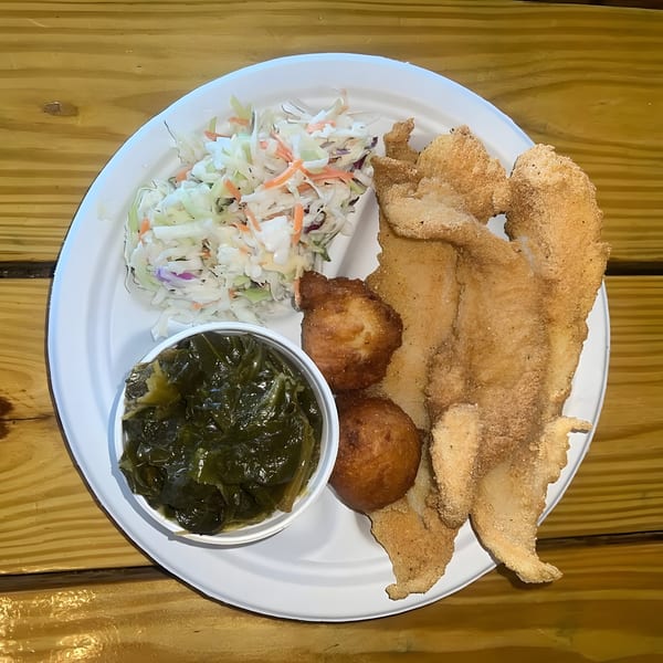 A Hank's Catfish & BBQ plate with fried catfish, hush puppies, coleslaw, and collard greens.